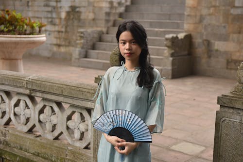 Young Model Holding a Floral Fan Wearing a Traditional Ao Dai Tunic