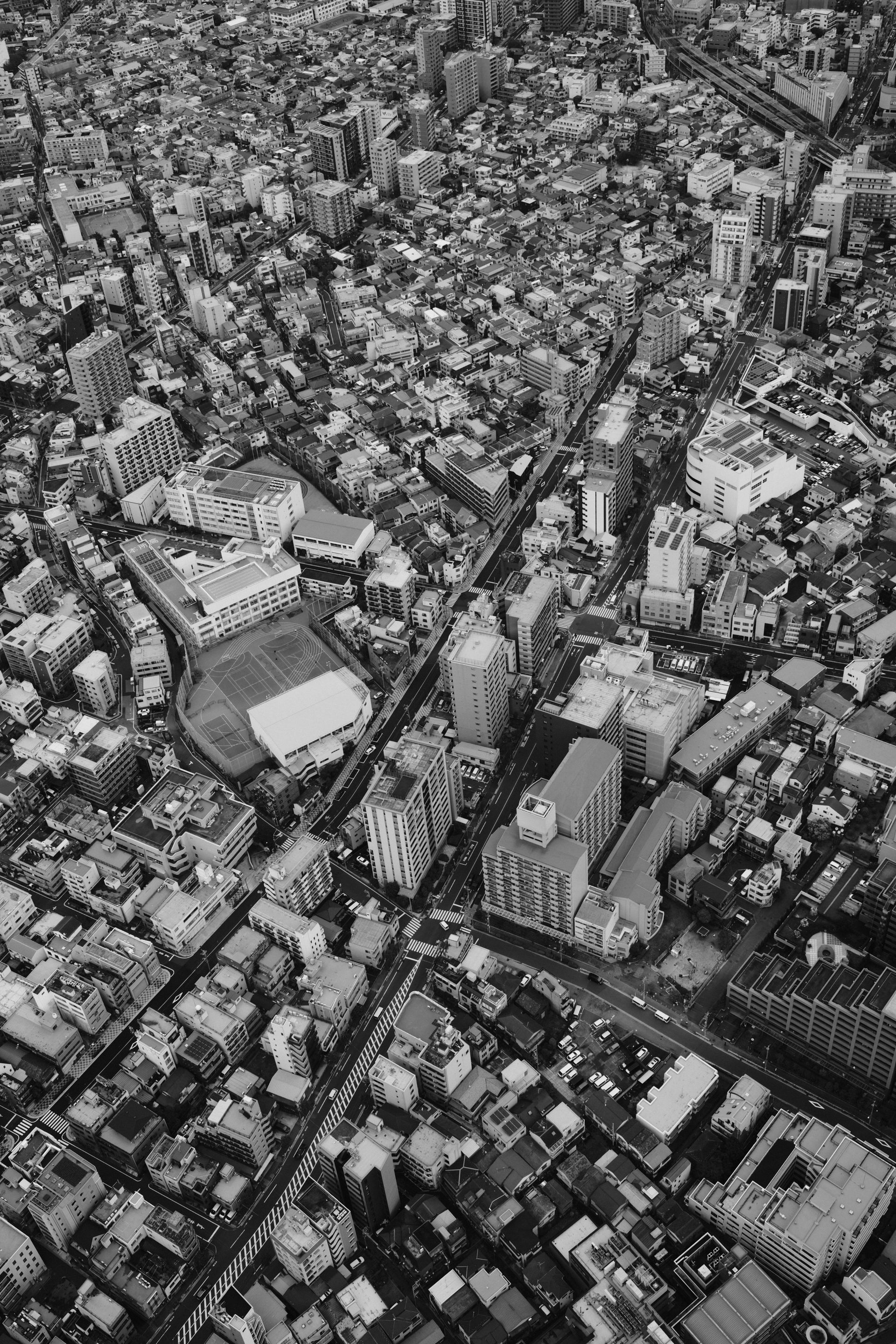 A dramatic aerial view of a densely packed urban cityscape in monochrome tones.