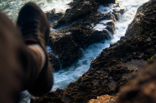 Free Leg of a Man Sitting on a Mountain and a Stream Below  Stock Photo