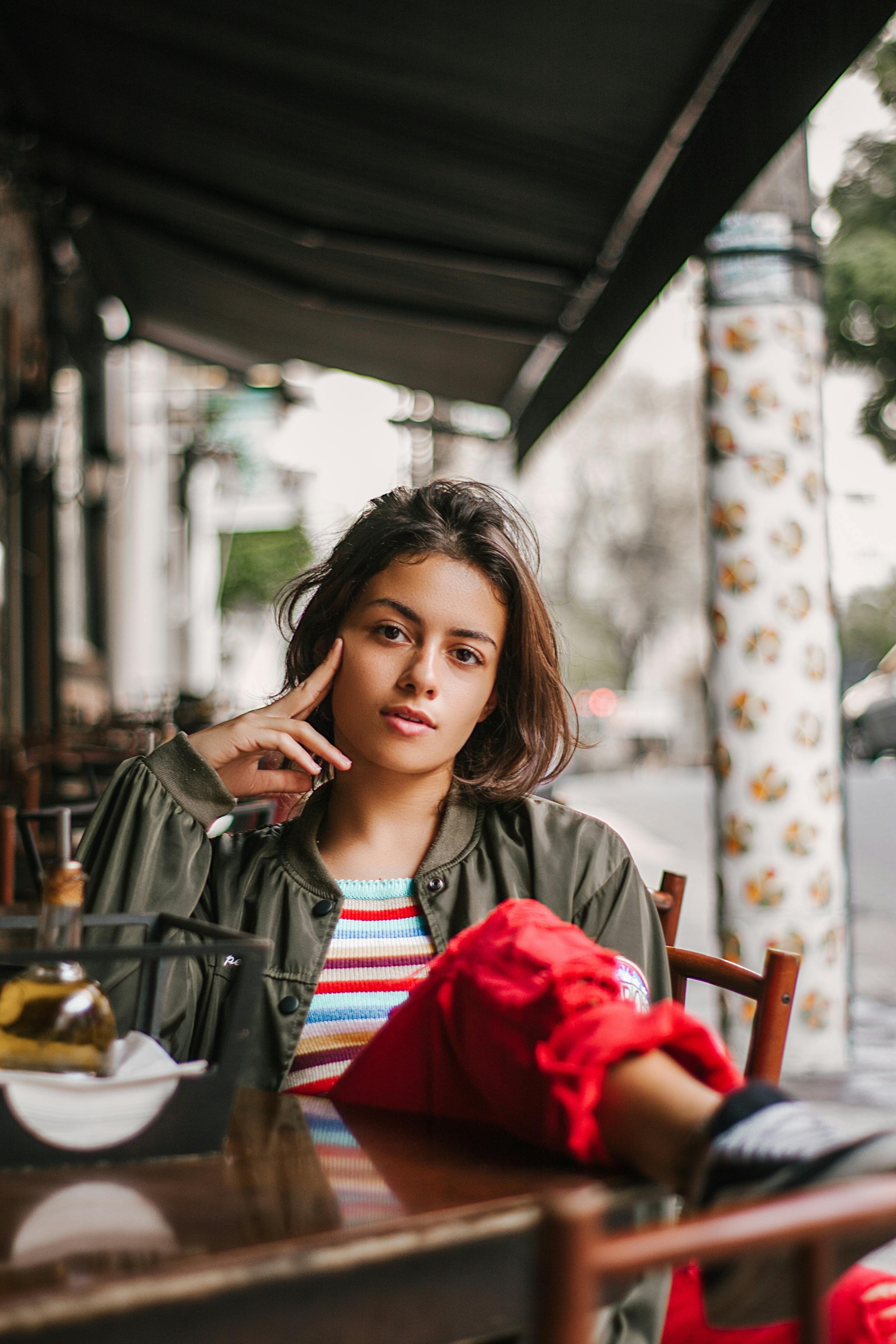 一位女士坐在户外咖啡馆，神情放松，散发着休闲与自信的风格