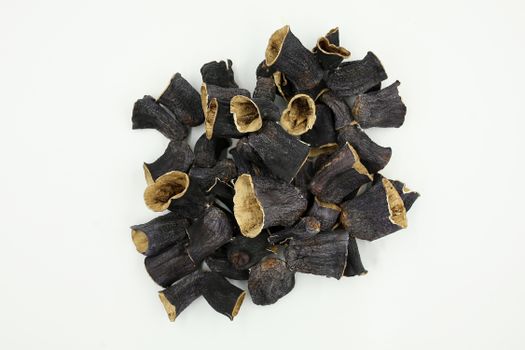 Collection of dried black vegetable slices on a white background, ideal for food photography and culinary projects.