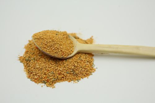 Free Top view of a wooden spoon with bee pollen scattered on a white background. Perfect for food photography. Stock Photo