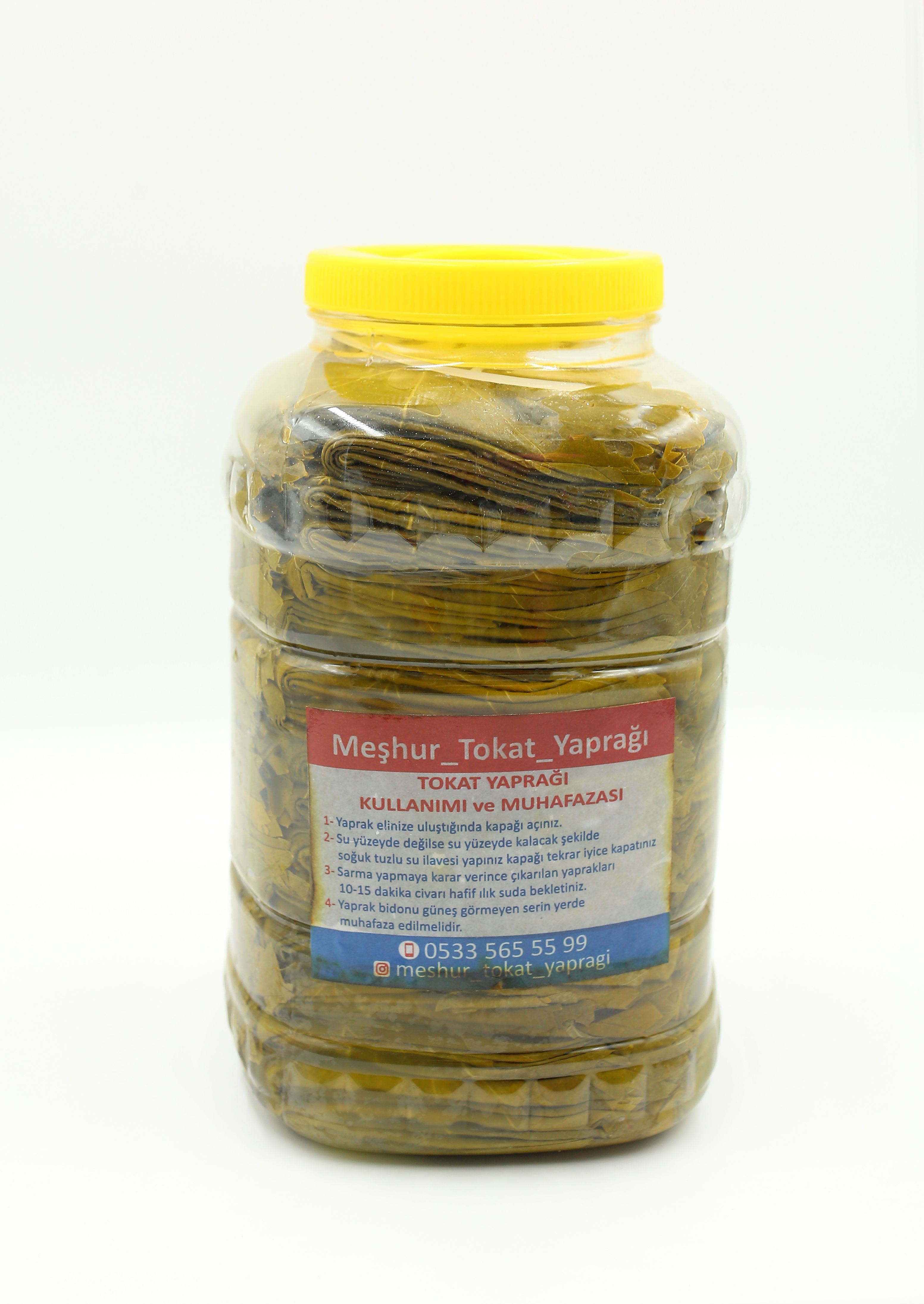 A clear plastic jar filled with pickled grape leaves, labeled with Turkish text.
