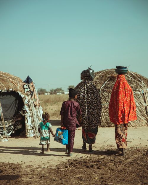 Free A family of women and children in traditional attire walking in a tribal village setting. Stock Photo