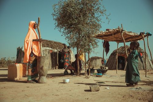 Free A vibrant scene depicting daily life in an African tribal village with traditional huts and local people. Stock Photo