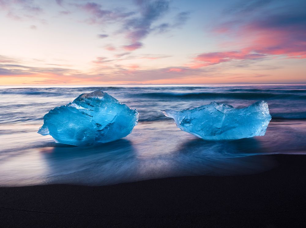 Diamond Beach: icebergs azules sobre arena volcánica negra al atardecer