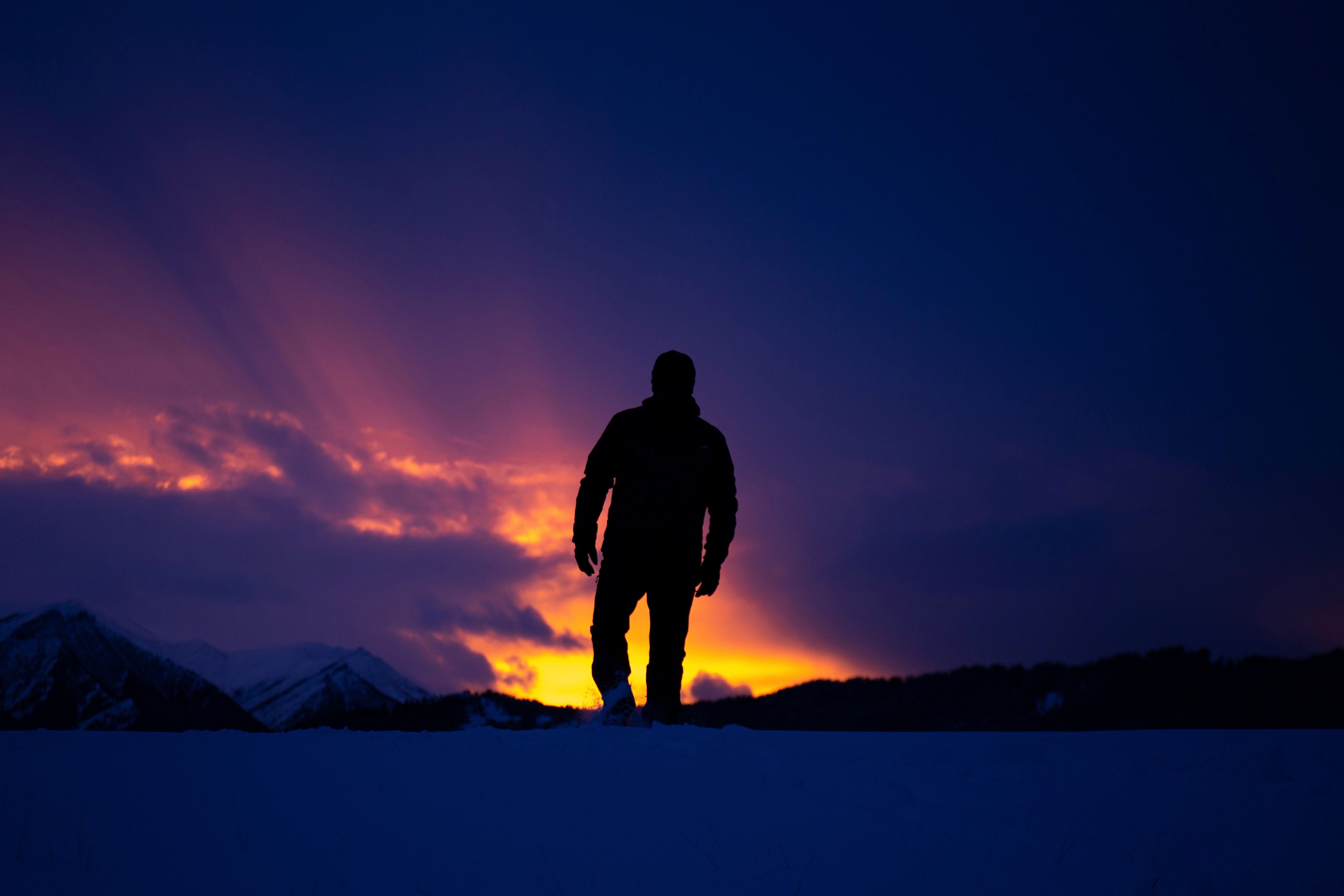 A powerful silhouette of a man against a winter sunset in Şavşat, Türkiye, with vibrant colors and snowy landscape.