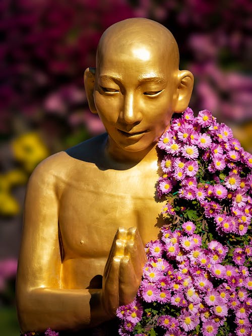 Blooming Flowers on Golden Buddha Statue in Park