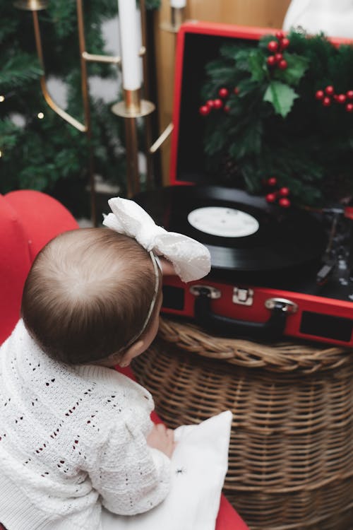 Cute Baby Girl near Vinyl Record Player in Christmas Home