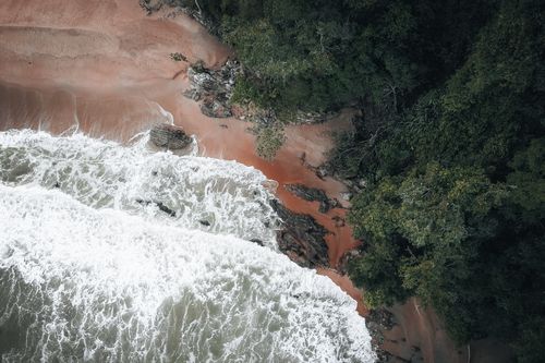 Free Stunning aerial shot showcasing Chukai, Terengganu's beautiful coastline with lush greenery and vibrant ocean waves. Stock Photo