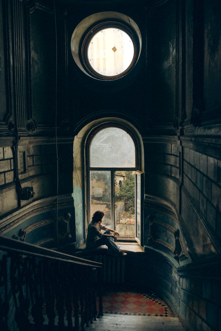 Person Sitting On A Staircase Windowsill 