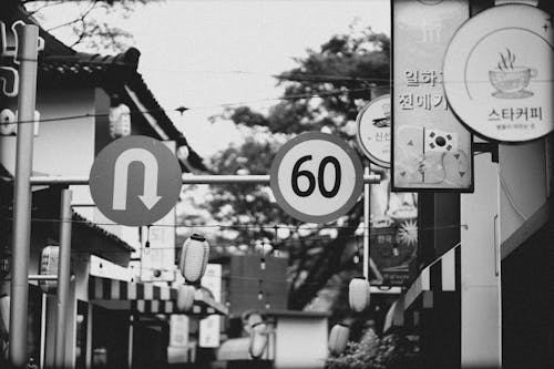 Black and White Photo of Signs between Buildings in City 