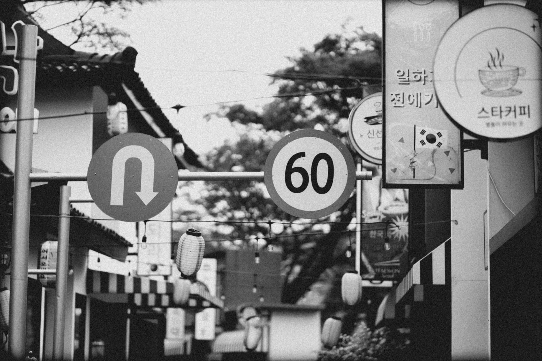 Grayscale image of a Korean street with road signs and urban architecture.