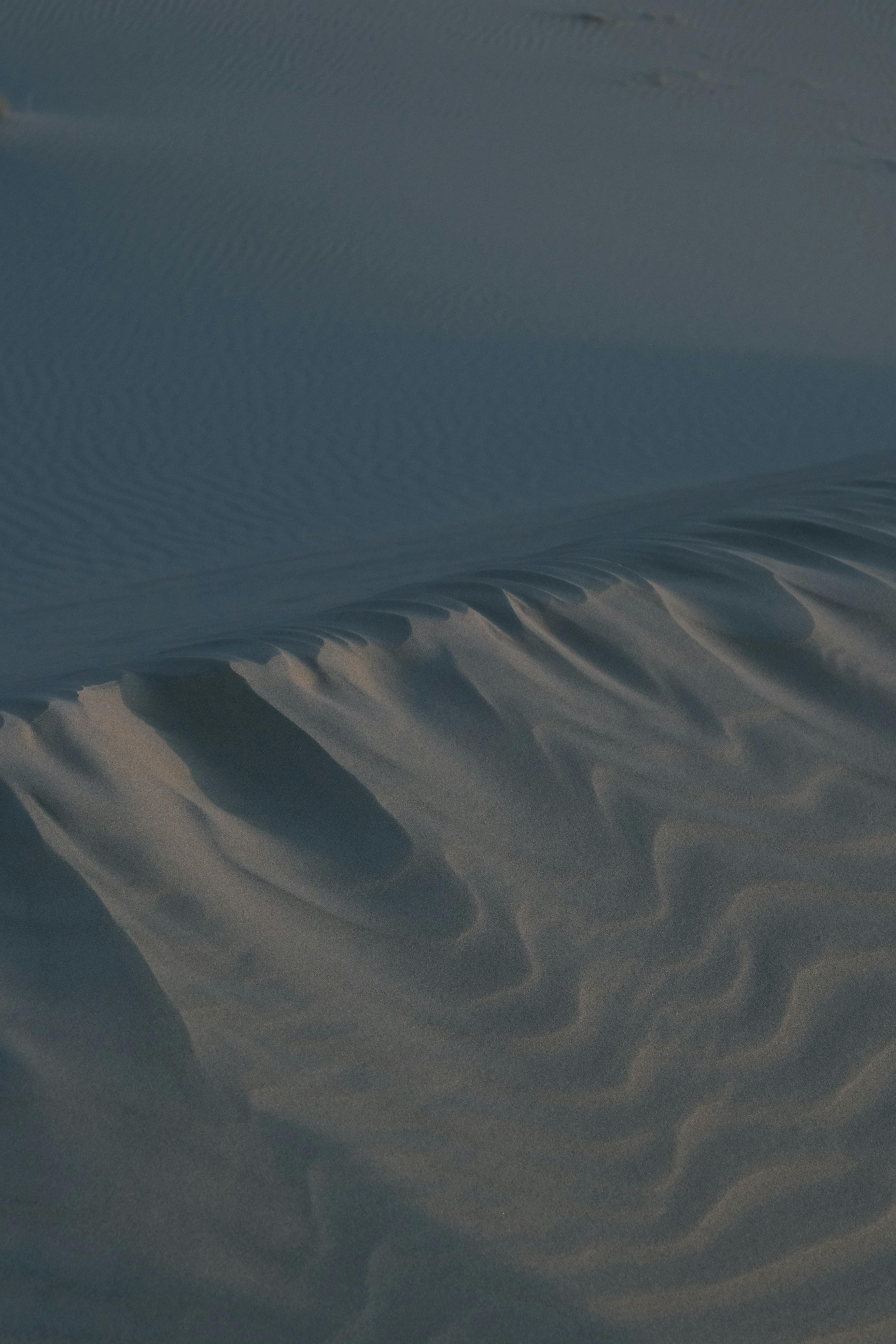 Aerial view showcasing wind-sculpted sand dunes, capturing natural desert landscape texture.