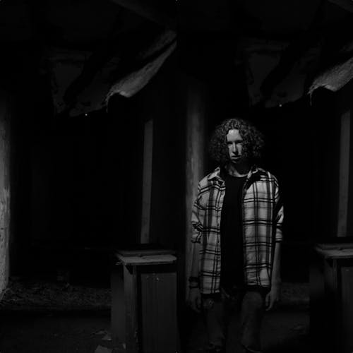 Man with Long Curly Hair Standing in Dark