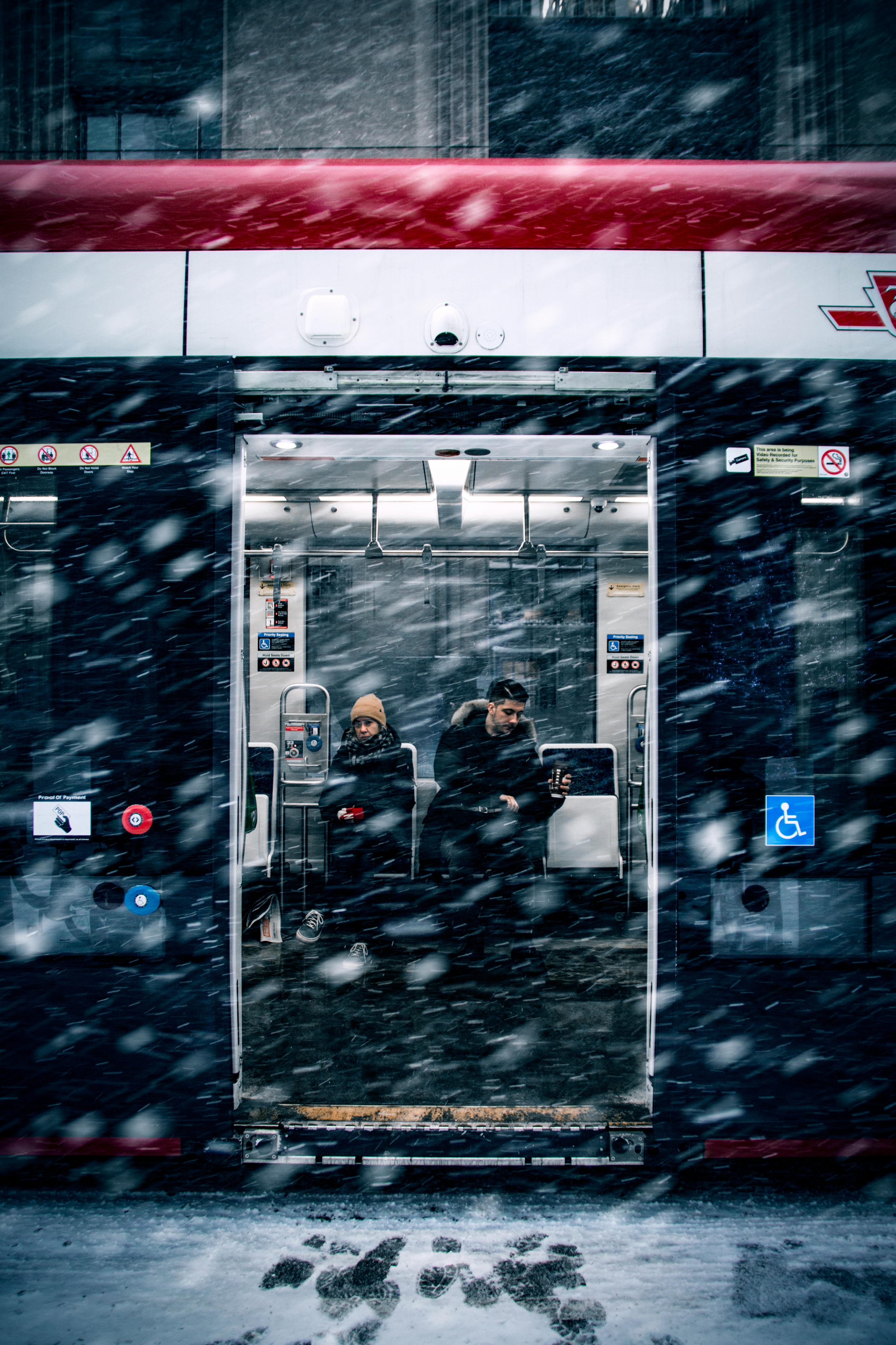 Passengers wait inside an open subway door during a heavy snowstorm in winter.