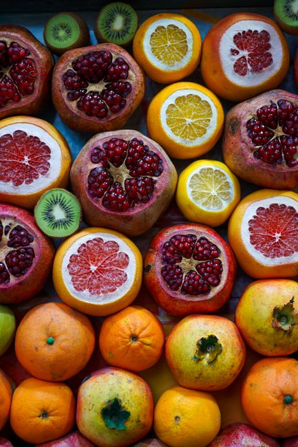 A vibrant display of sliced tropical fruits including oranges, pomegranates, and kiwis from a top view.