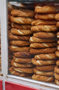 Rows of freshly baked bagels displayed in a bakery window, showcasing crisp textures and golden hues.