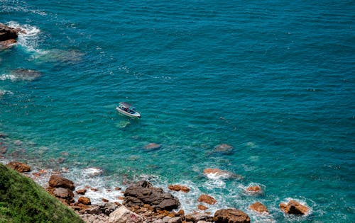 Boat on a Turquoise Sea, and a Rocky Coast