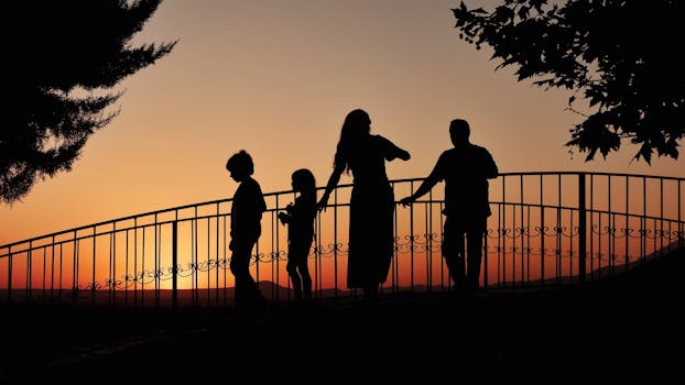 A family enjoying a beautiful sunset silhouetted on a bridge, creating a heartwarming scene.
