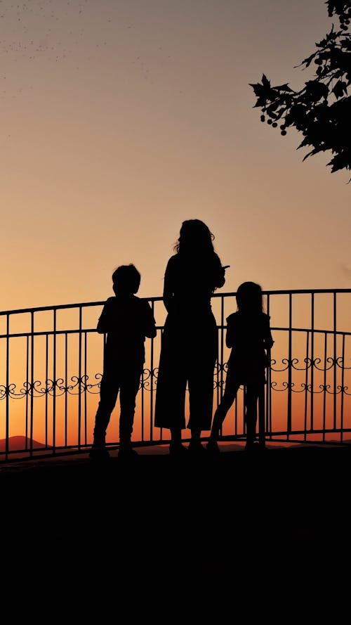 Free Woman and Children Looking at Sunset on Terrace Stock Photo