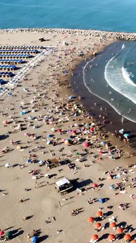 Vibrant aerial shot of Mar del Plata beach, Argentina, teeming with people enjoying summer sun and sea.