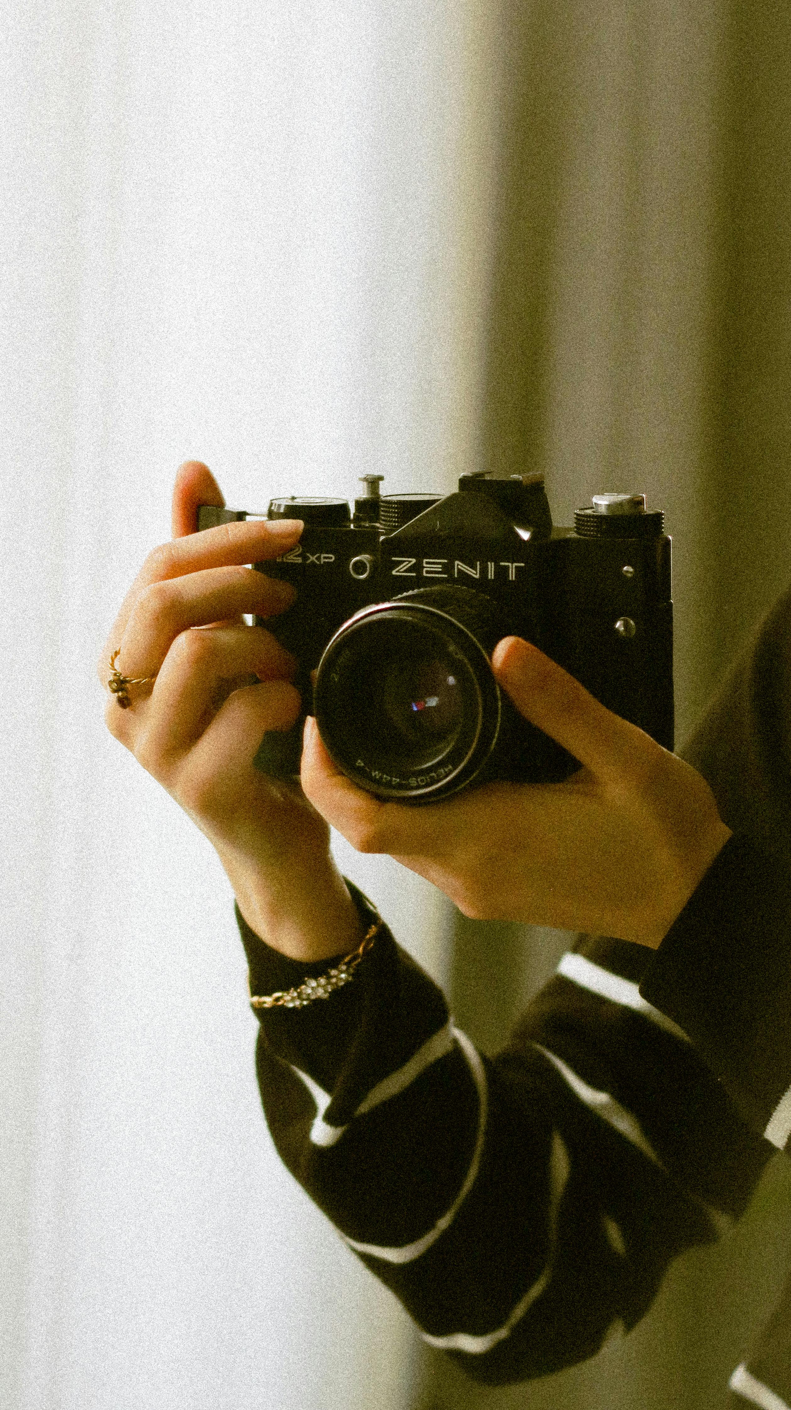 Close-up of a vintage Zenit camera held by a woman, evoking nostalgia.