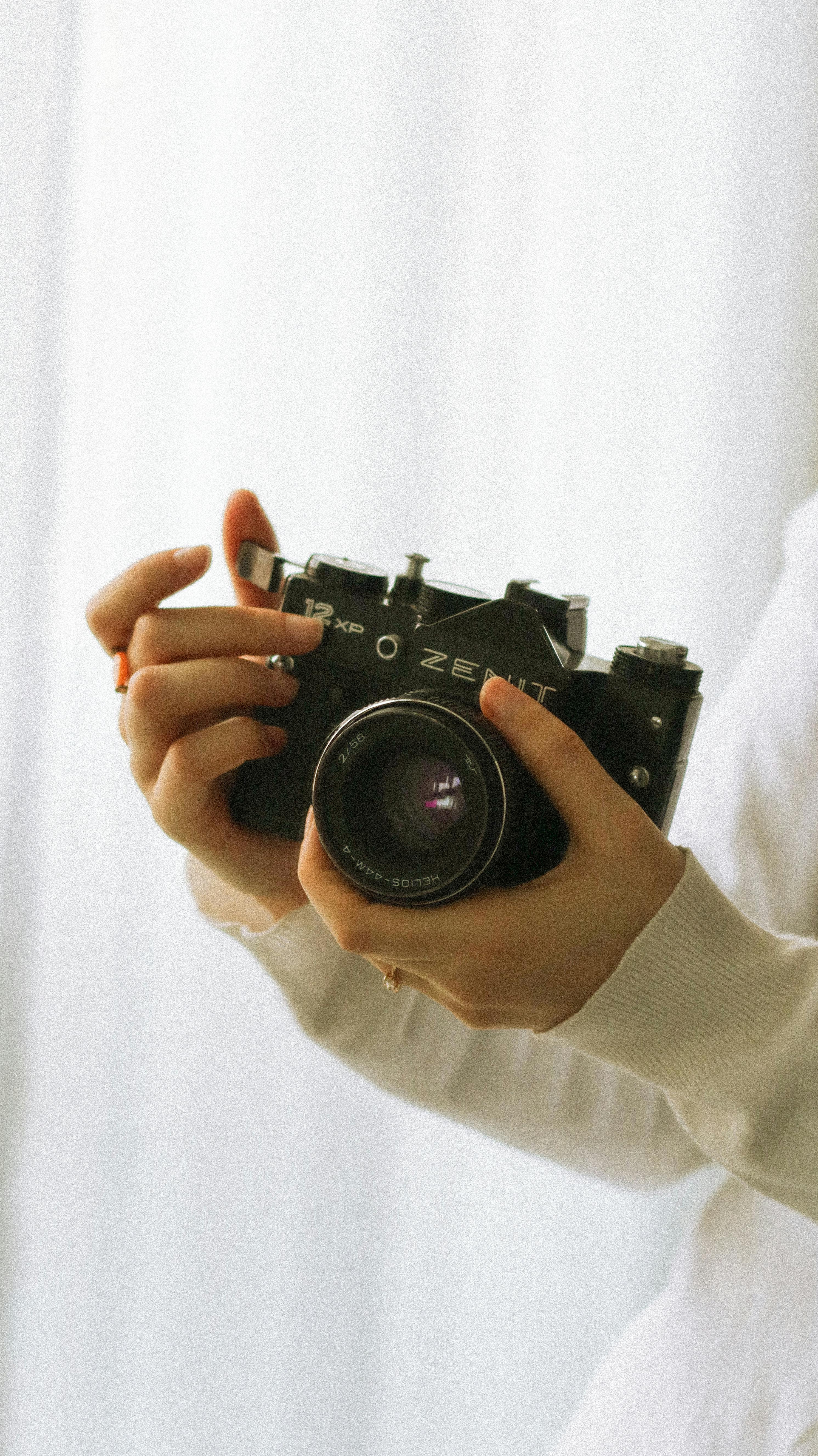 Close-up of a woman holding a vintage Zenit camera, evoking nostalgia and classic photography.