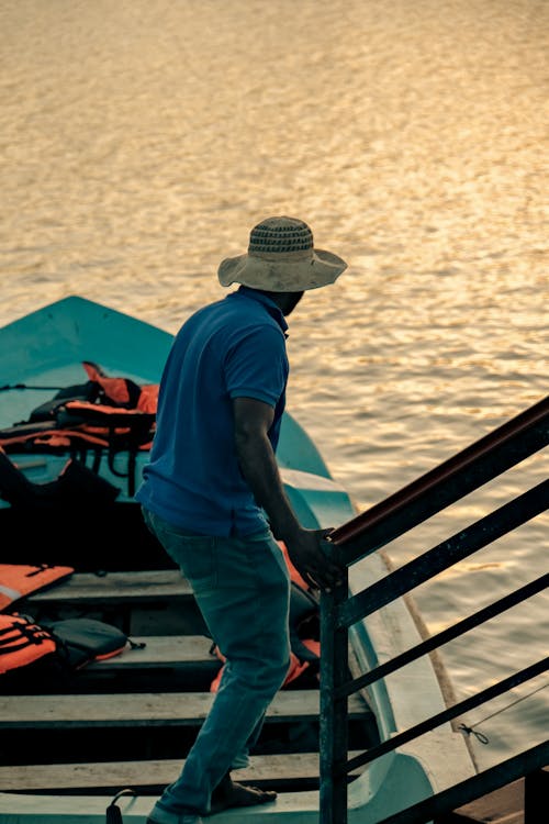 Man with Hat in Blue Polo Shirt Standing on Boat