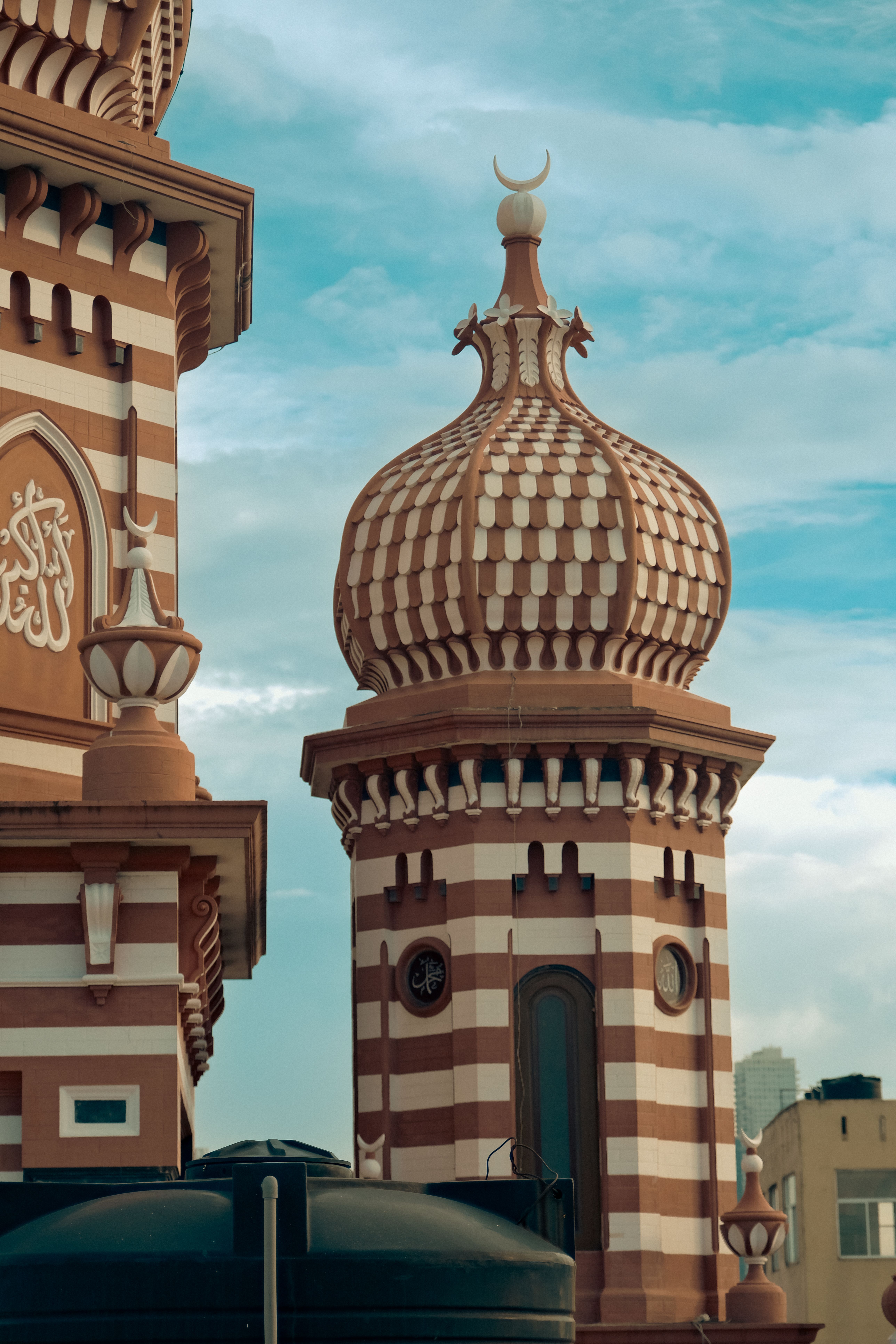 A striking view of the iconic red and white minaret of Jami Ul-Alfar Mosque in Colombo under a clear sky.