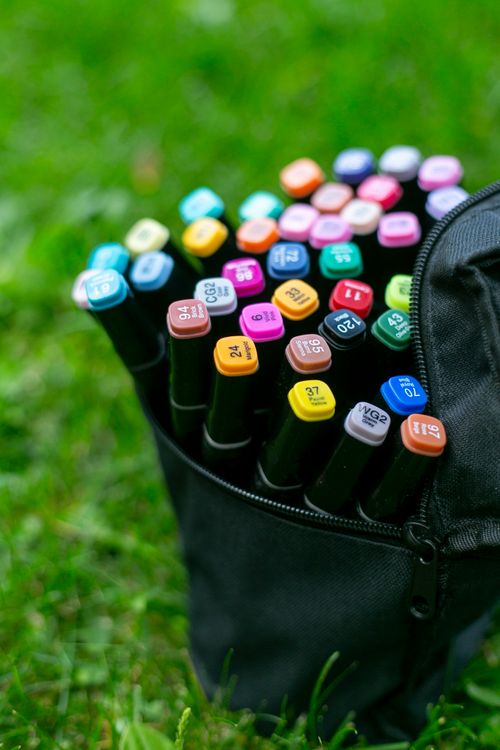 Free Close-up of colorful markers in a black bag on vibrant green grass. Stock Photo