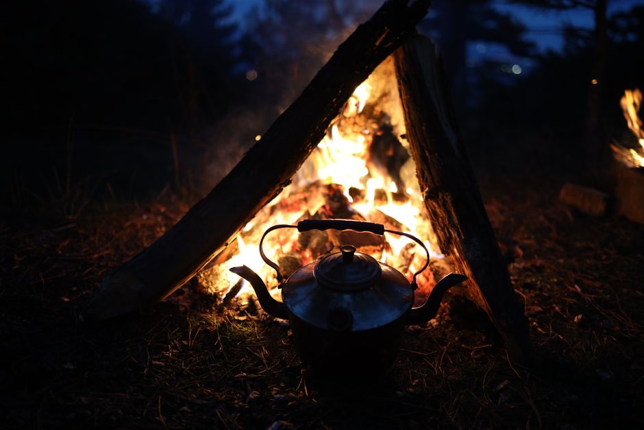 How Electric Kettles with Temperature Control Elevate Pour Over Brewing A warm campfire with a kettle, set against the tranquility of nighttime outdoors.