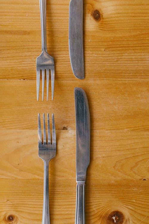 Top View of Forks and Knives Lying on a Wooden Table 