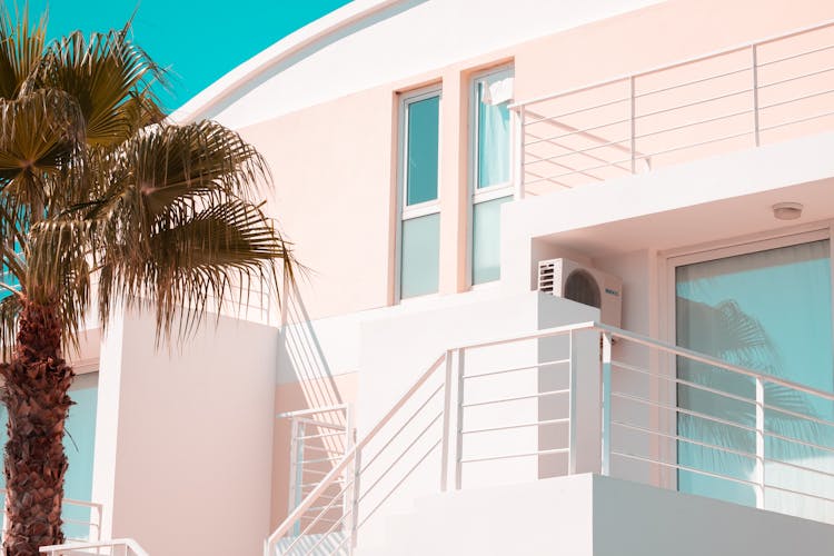 Facade Of A Pink House With A Palm Tree In The Front Yard