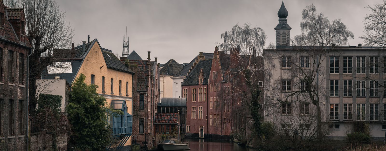 Atmospheric view of a historic canal and old town architecture in Ghent, Belgium.