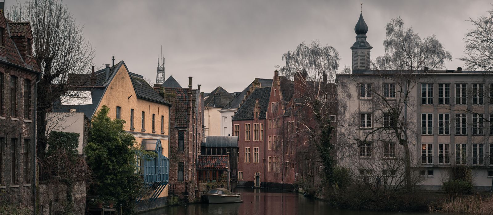 Atmospheric view of a historic canal and old town architecture in Ghent, Belgium.