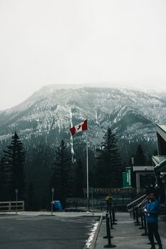 Canadian flag waves against a snowy mountain backdrop in Banff, capturing winter's serene beauty.