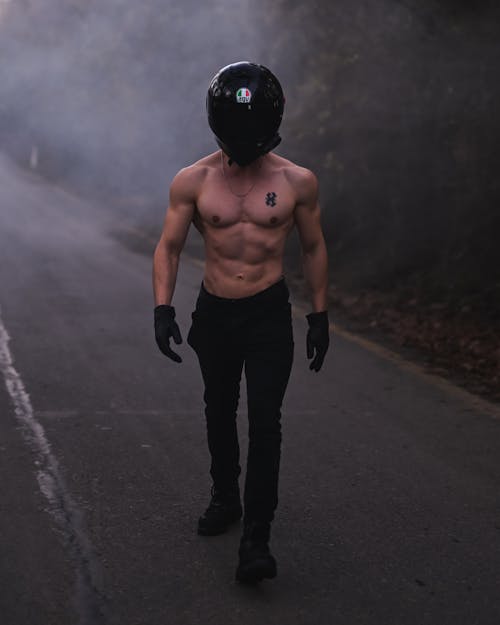 Shirtless Motorcyclist Walking Down the Road