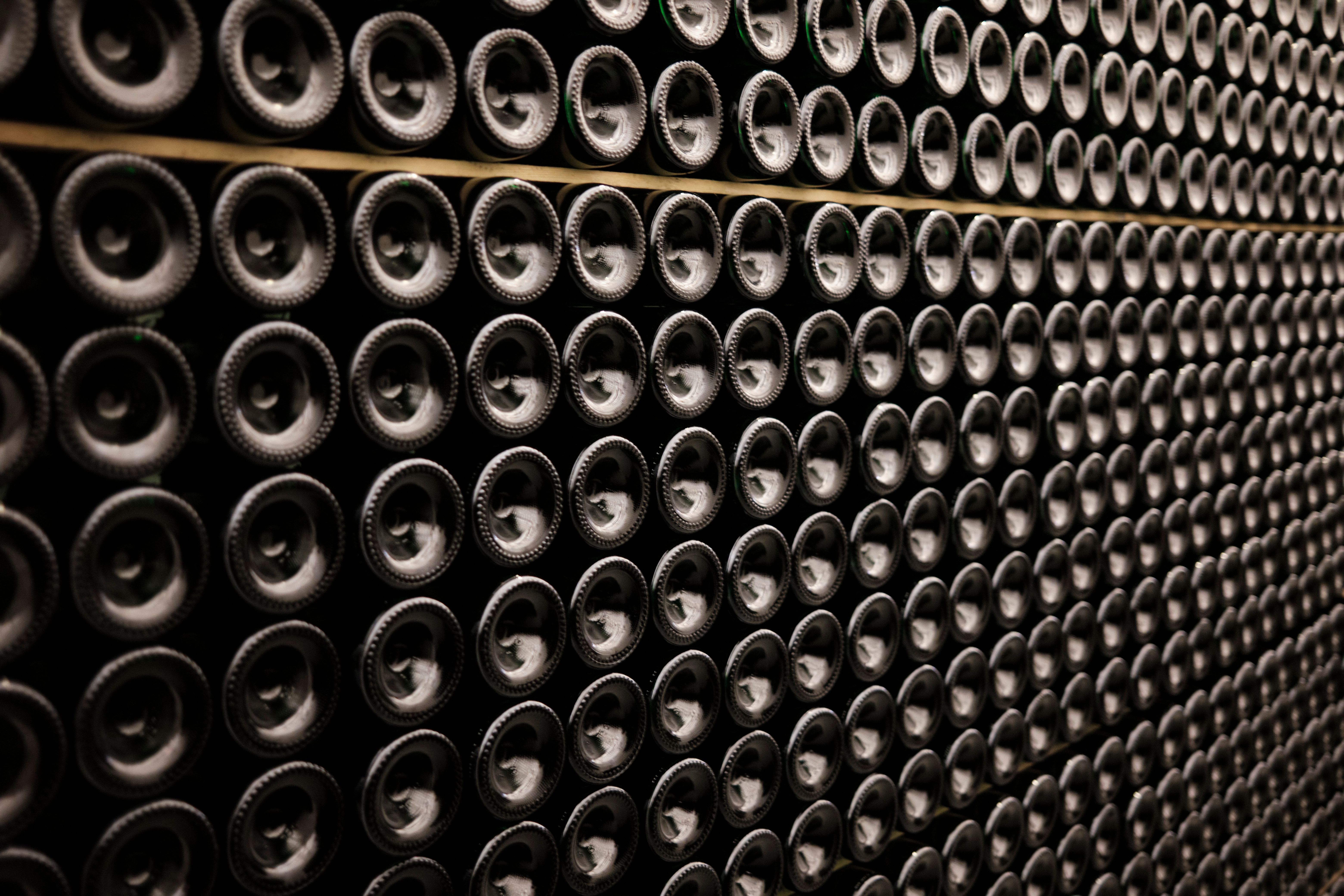 Hileras de botellas de vino francés en una bodega con poca luz.