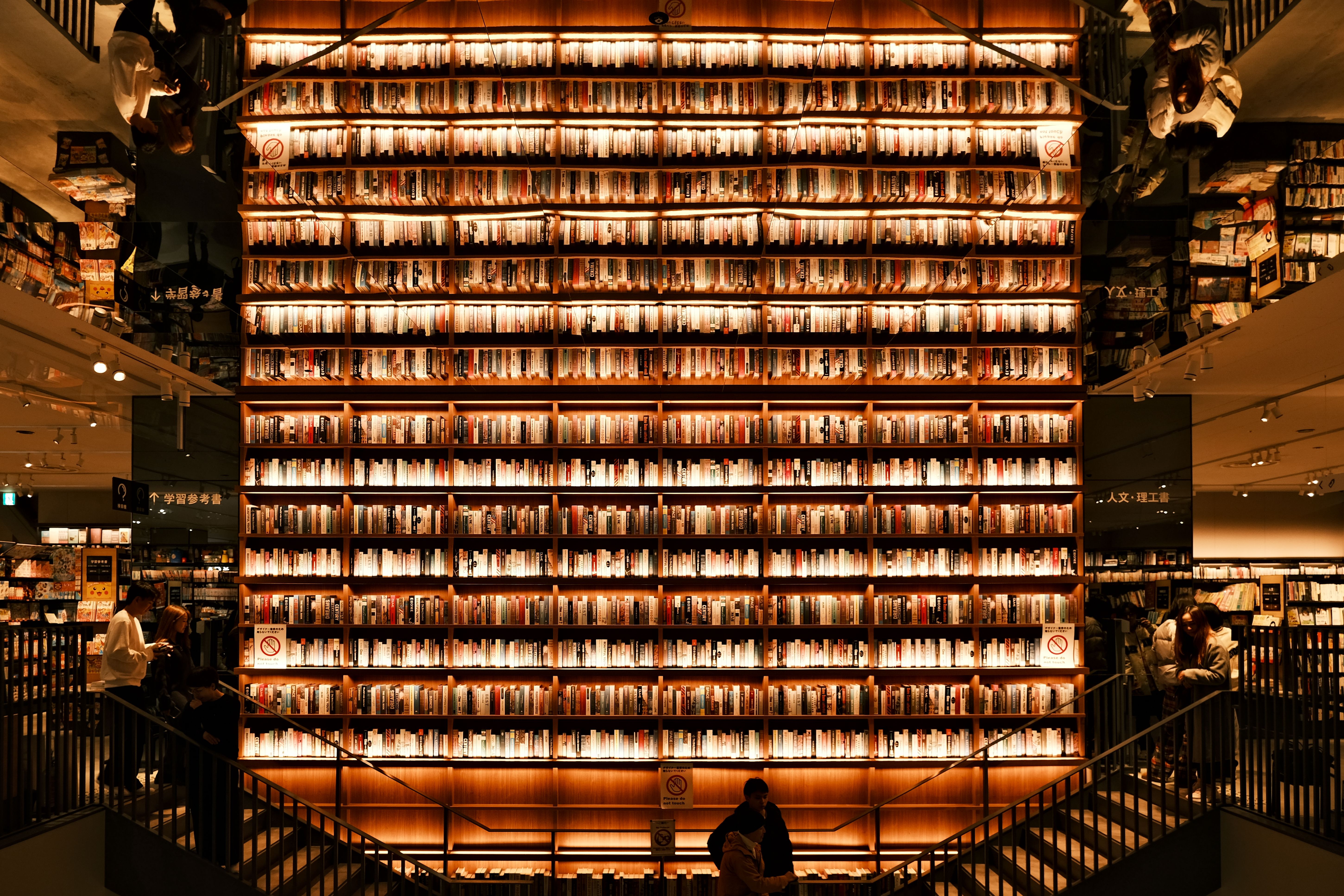 Cozy Lisbon bookstore with stacked shelves and warm lighting, two people chatting by the window
