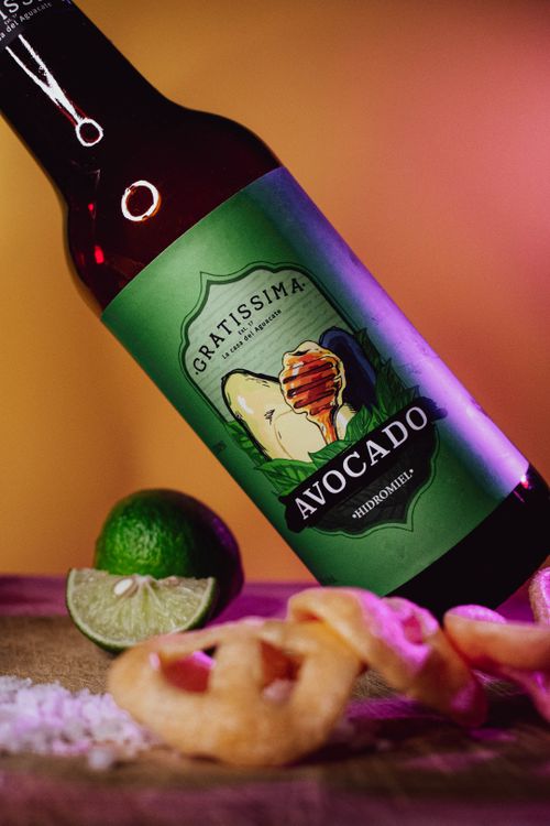 Free Vibrant avocado mead bottle on a wooden surface with lime and crispy snacks, perfect for beverage marketing. Stock Photo