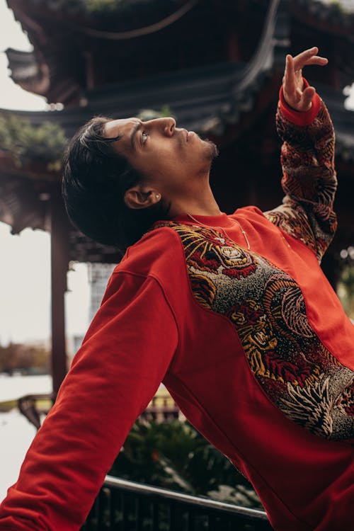 Man in a Red Sweatshirt Looking Up at the Sky