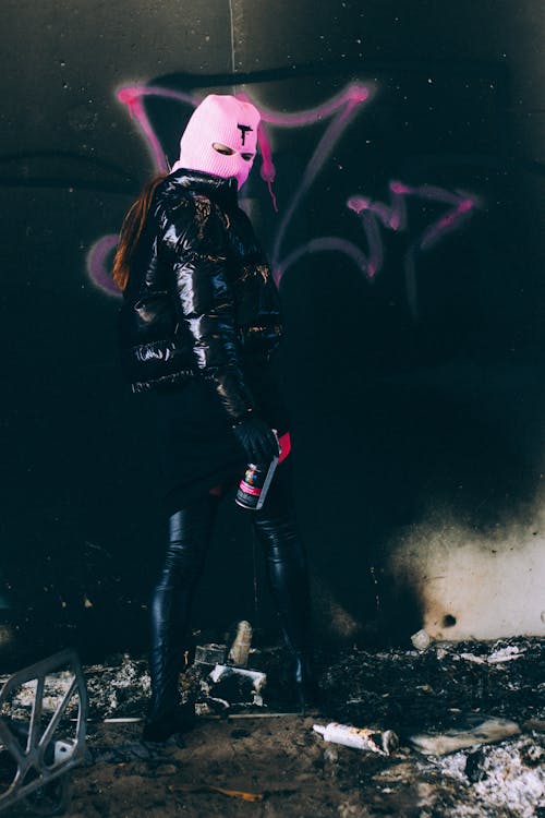 Woman in a Pink Balaclava Spray-painting a Graffiti Tag