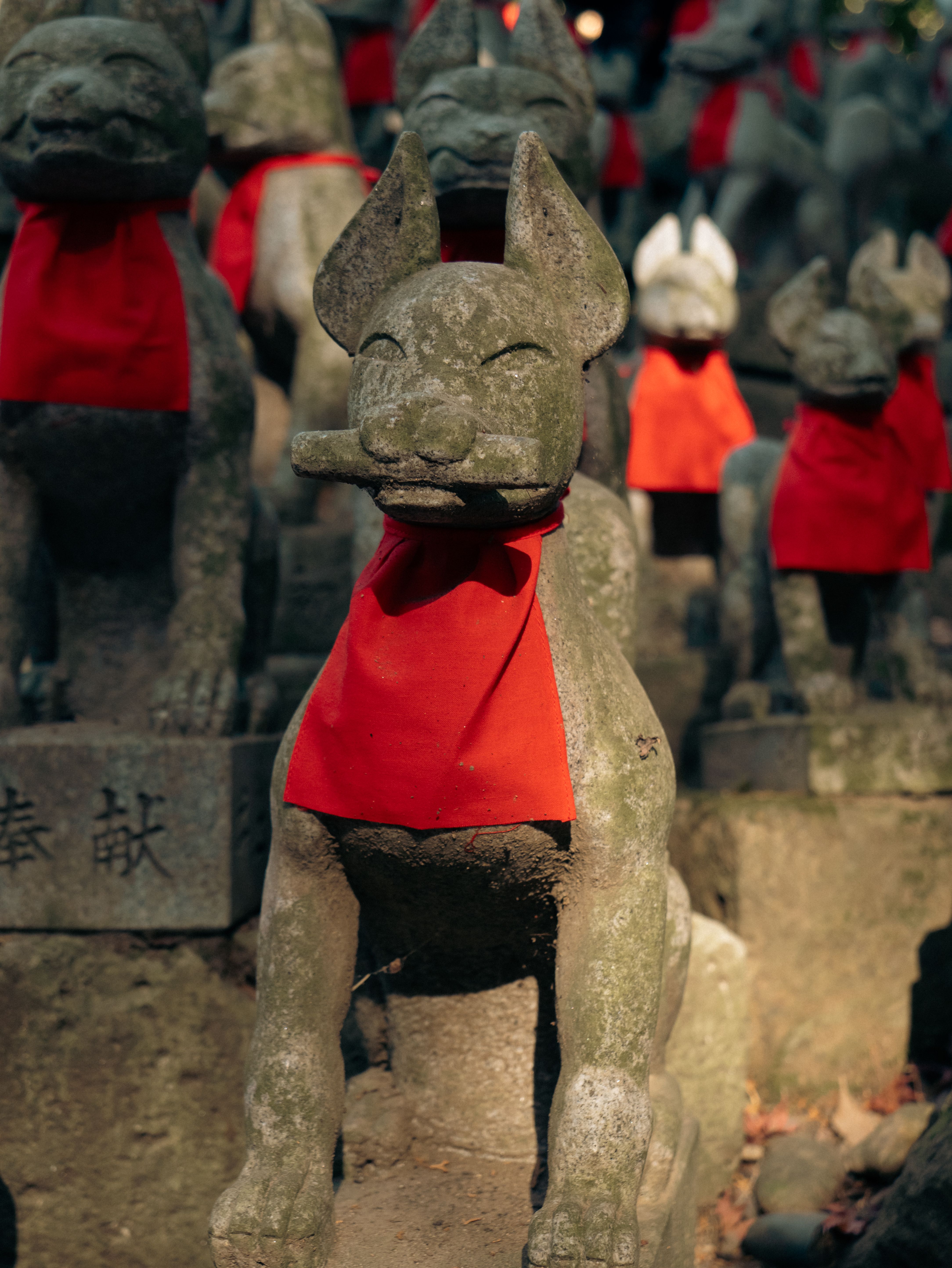 Close-up of stone fox statues with red bibs at Toyokawa Inari, showcasing traditional Japanese spirituality.