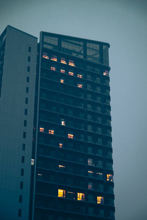 Illuminated Windows of a High-Rise Building in Evening Fog 