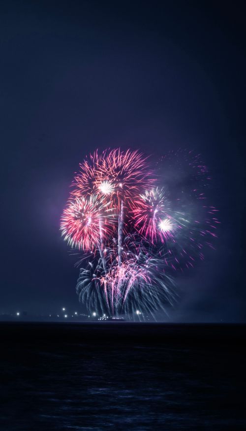 Free Colorful fireworks bursting over the ocean during nighttime festivities, creating a vibrant celebration in the sky. Stock Photo