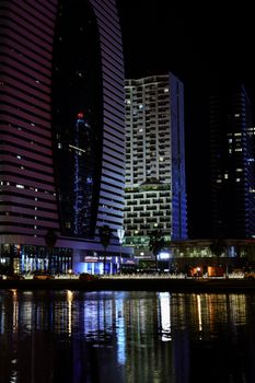 Stunning cityscape of Batumi with modern architecture reflecting on water at night.