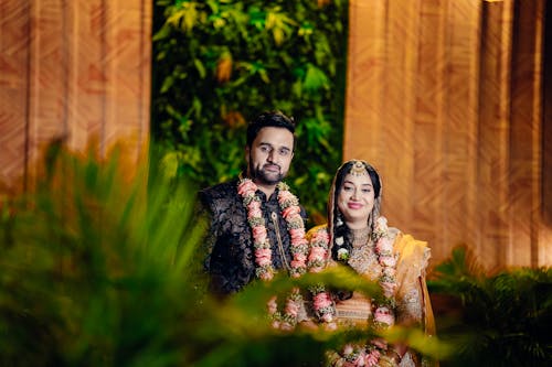 Newlywed Couple in Traditional Clothes and Flower Necklaces