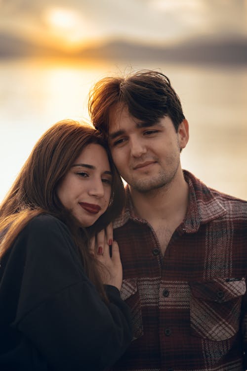 A Couple Standing Outside at Sunset and Hugging 