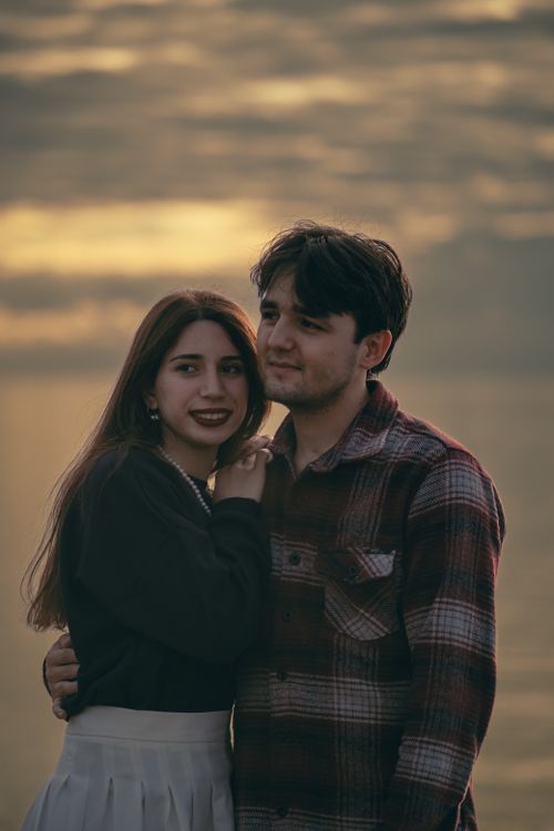 Free A loving couple embracing by the sea during a beautiful sunset, creating a romantic scene. Stock Photo